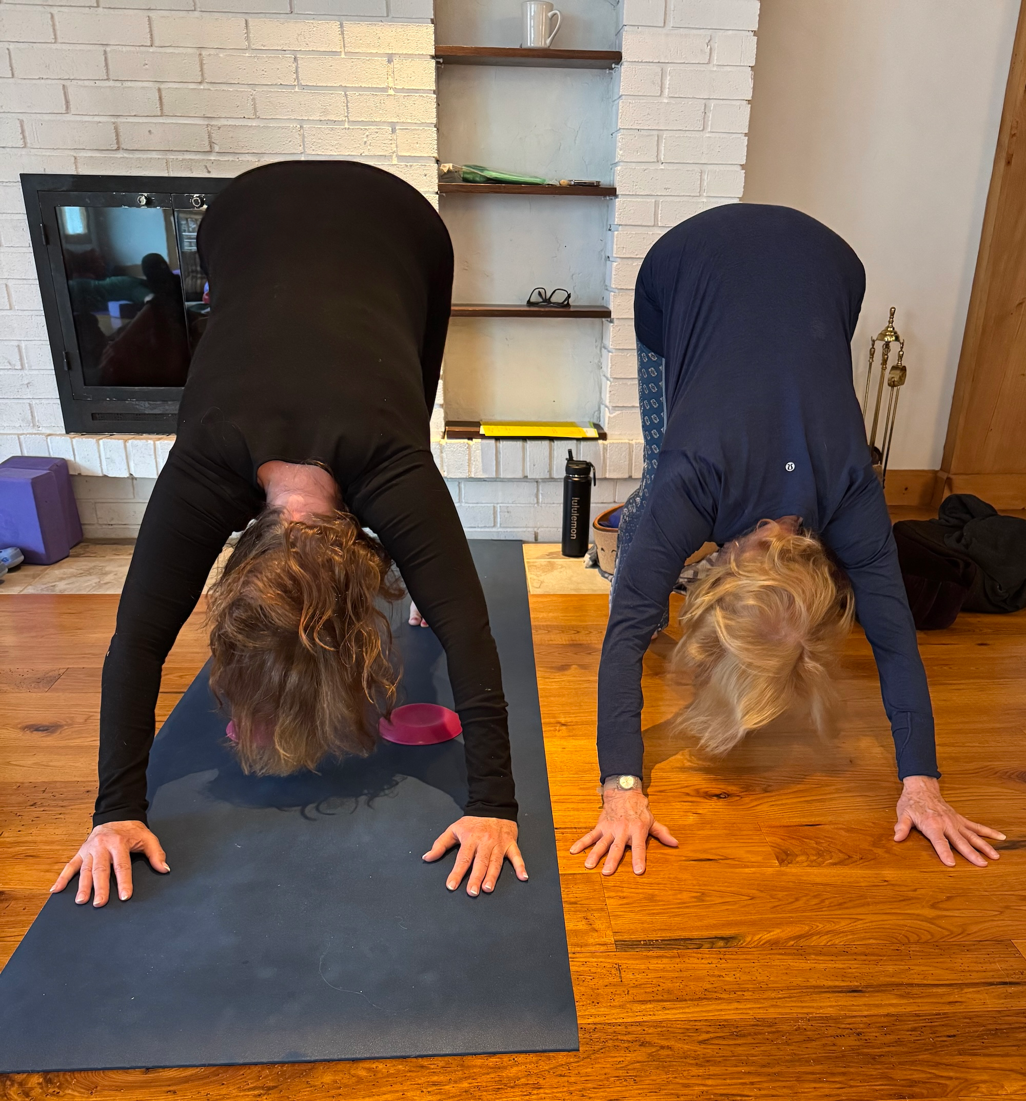 Mar Jean assists student with down dog pose