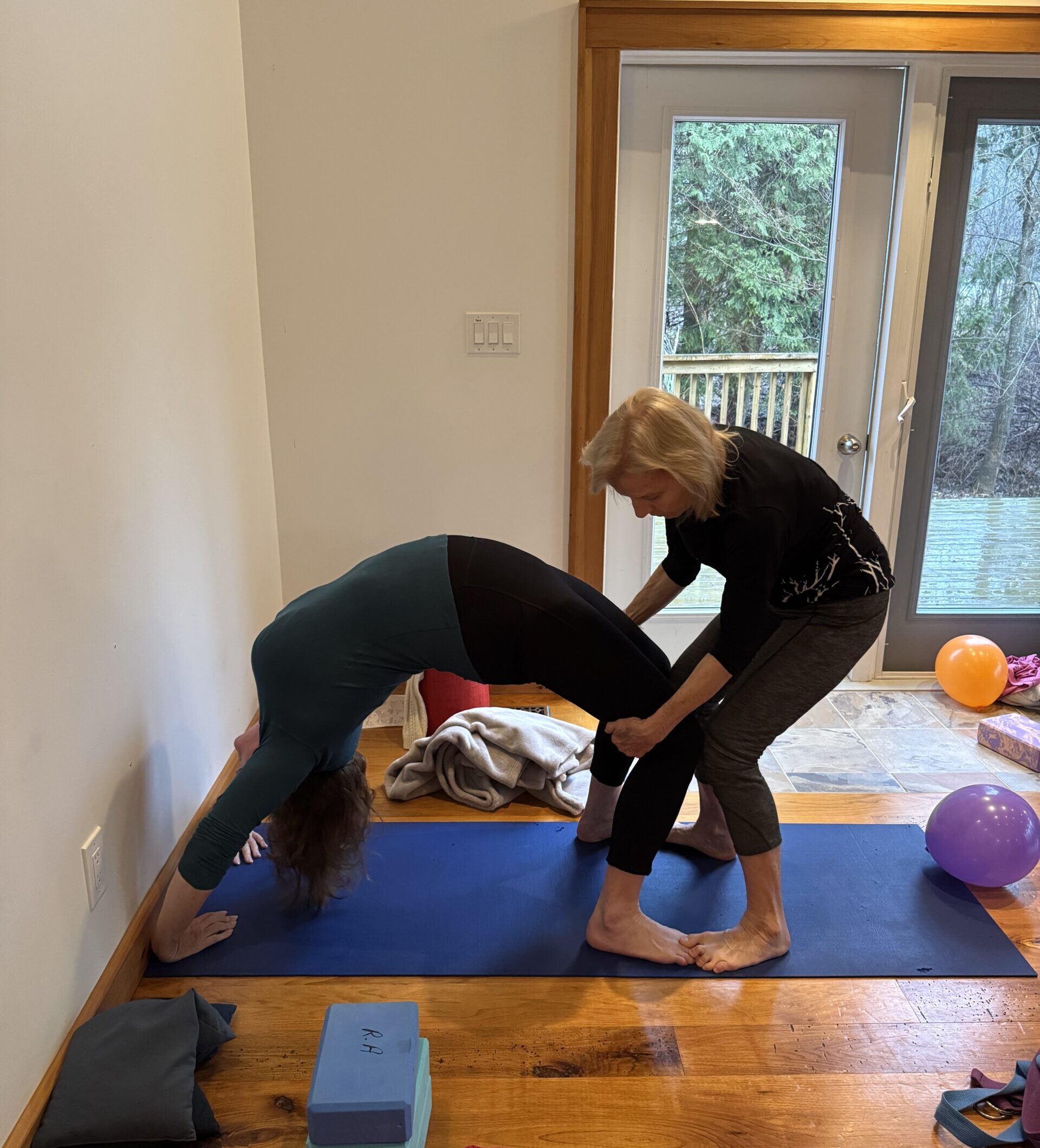 Mar Jean assisting a student with wheel pose
